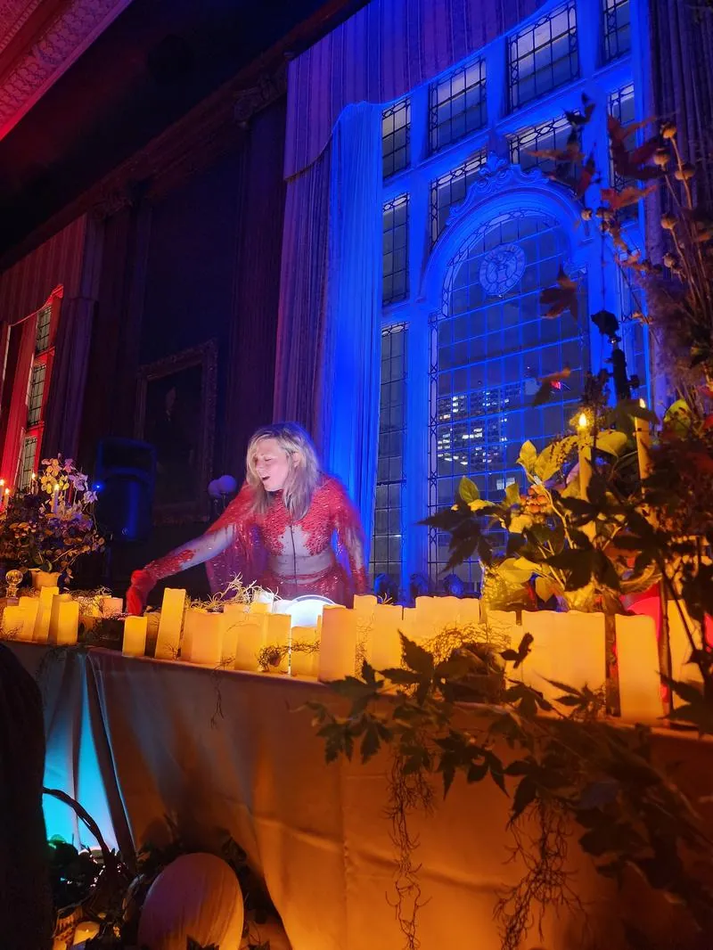 Daniela DJing behind a candle-covered table in the Mütter Museum ballroom, Halloween 2025