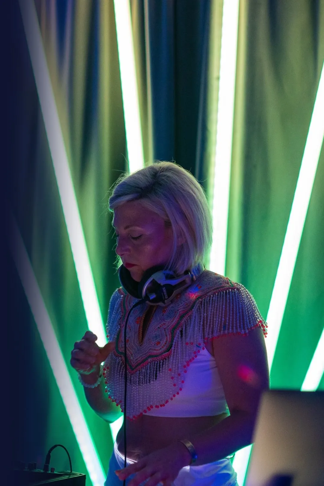Daniela DJing in front of glowing light tubes at Bogart House