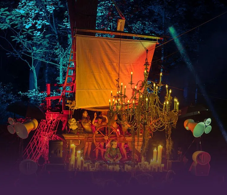The candlelit ship stage at CAMP Festival in the forest at night